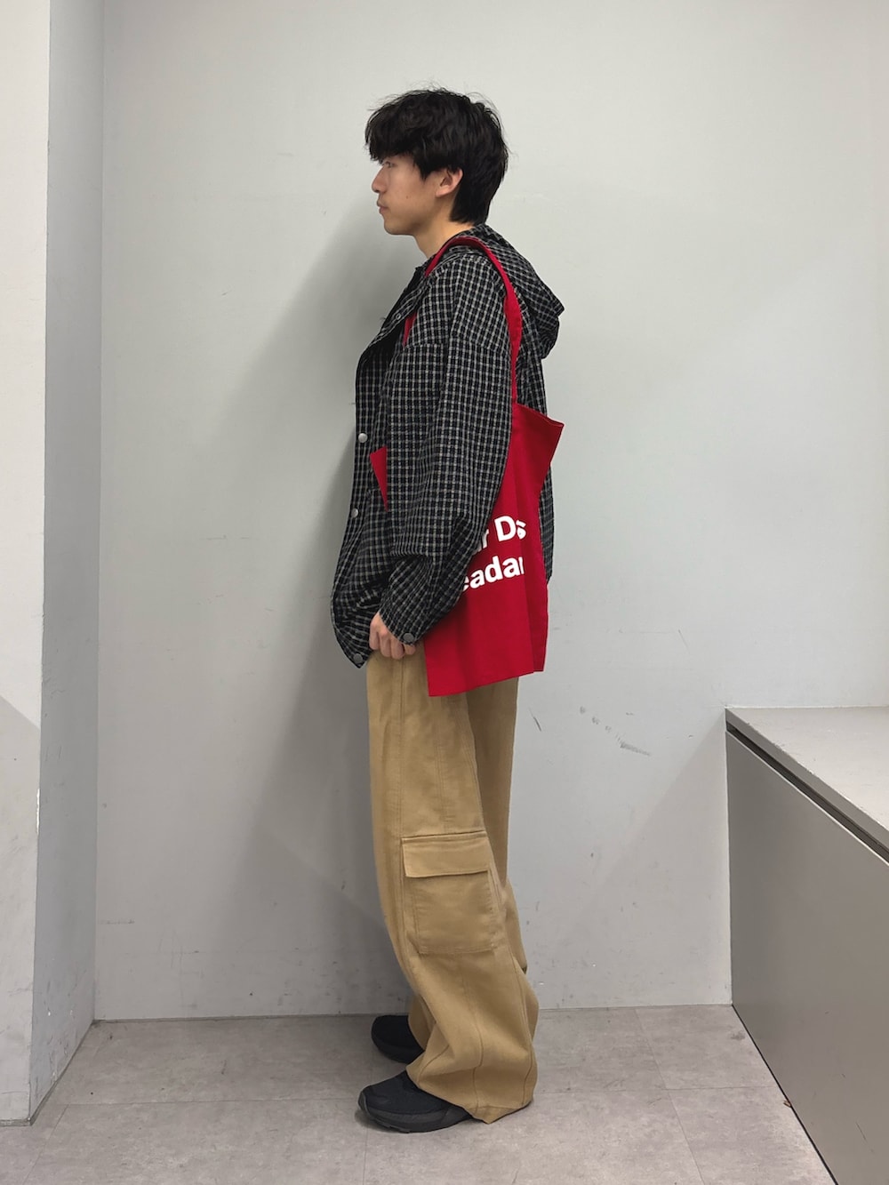 ブラック系のパーカー、ブラック系のTシャツ/カットソー、レッド系のトートバッグを着用したメンズの春コーディネートの2枚目の写真