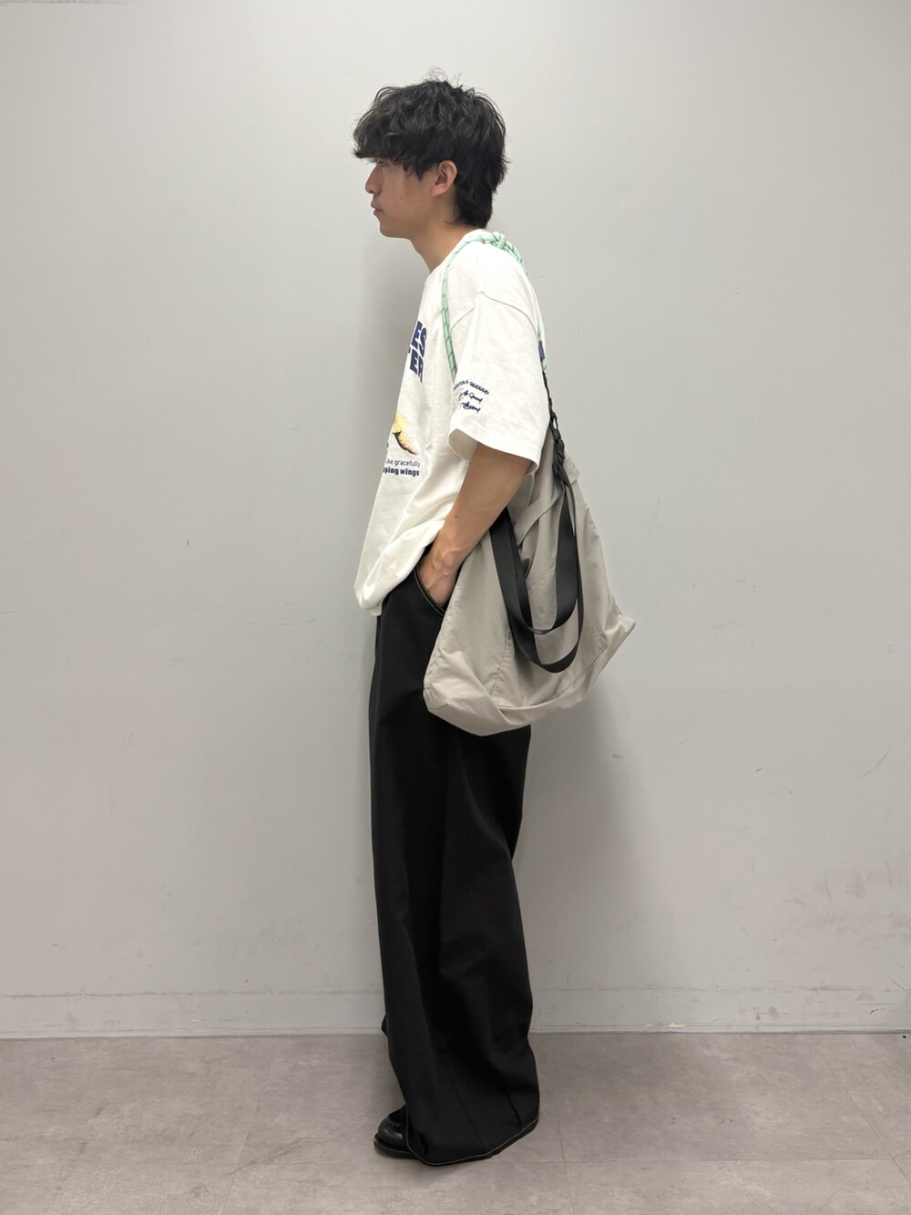ホワイト系のTシャツ/カットソー、グレー系のショルダーバッグ、ブラック系のチノパンツを着用したメンズの春コーディネートの2枚目の写真