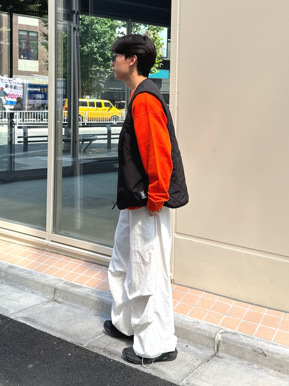 オレンジ系のスウェット、ブラック系のベスト、ホワイト系のその他パンツを着用したメンズの秋コーディネートの2枚目の写真