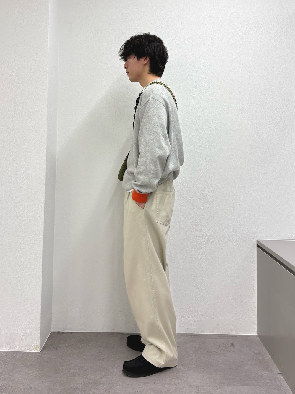 グレー系のニット/セーター、ホワイト系のチノパンツを着用したメンズの冬コーディネートの2枚目の写真