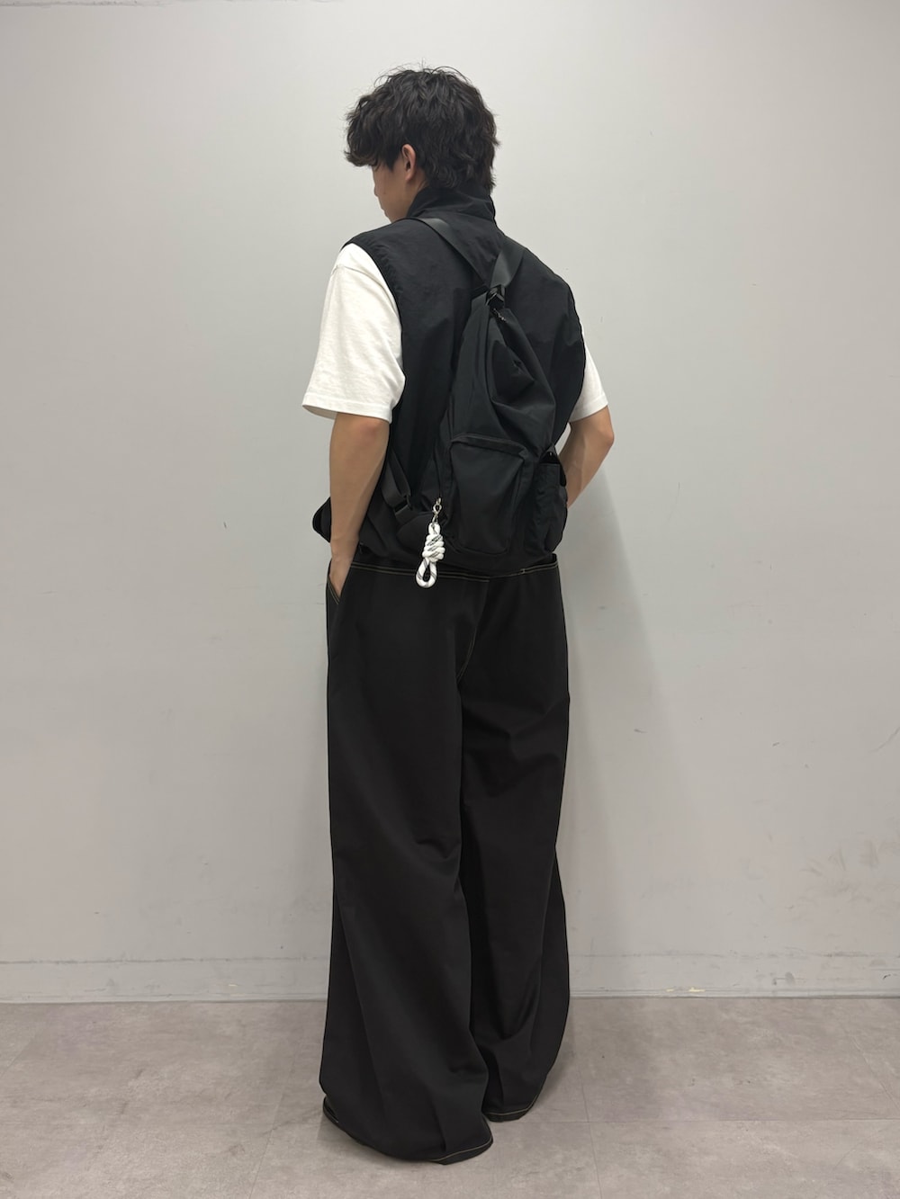 ブラック系のベスト、ブラック系のトートバッグ、ブラック系のチノパンツを着用したメンズの春コーディネートの2枚目の写真