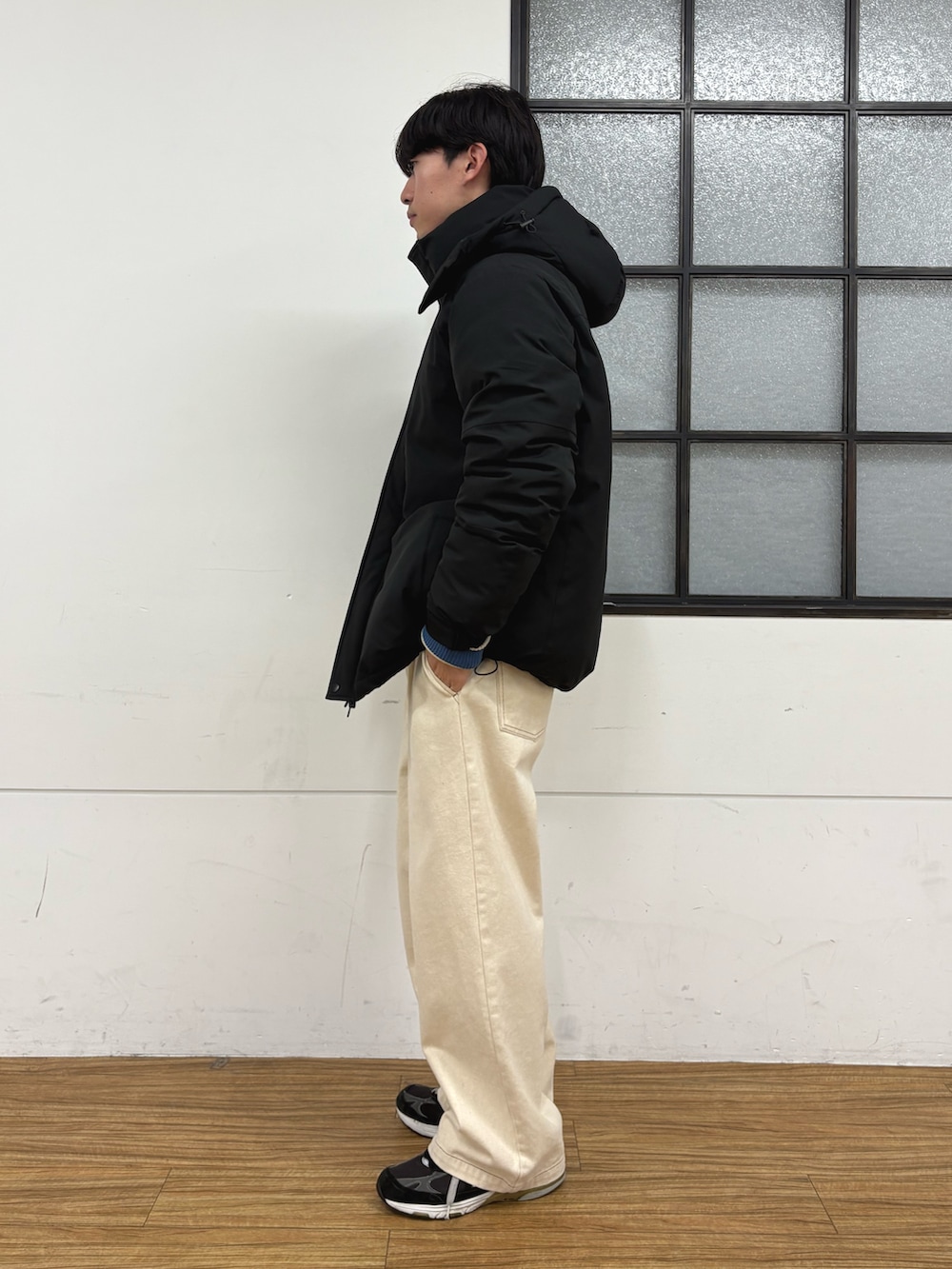 ブラック系のダウンジャケット/コート、ホワイト系のニット/セーター、ホワイト系のデニムパンツを着用したメンズの冬コーディネートの2枚目の写真