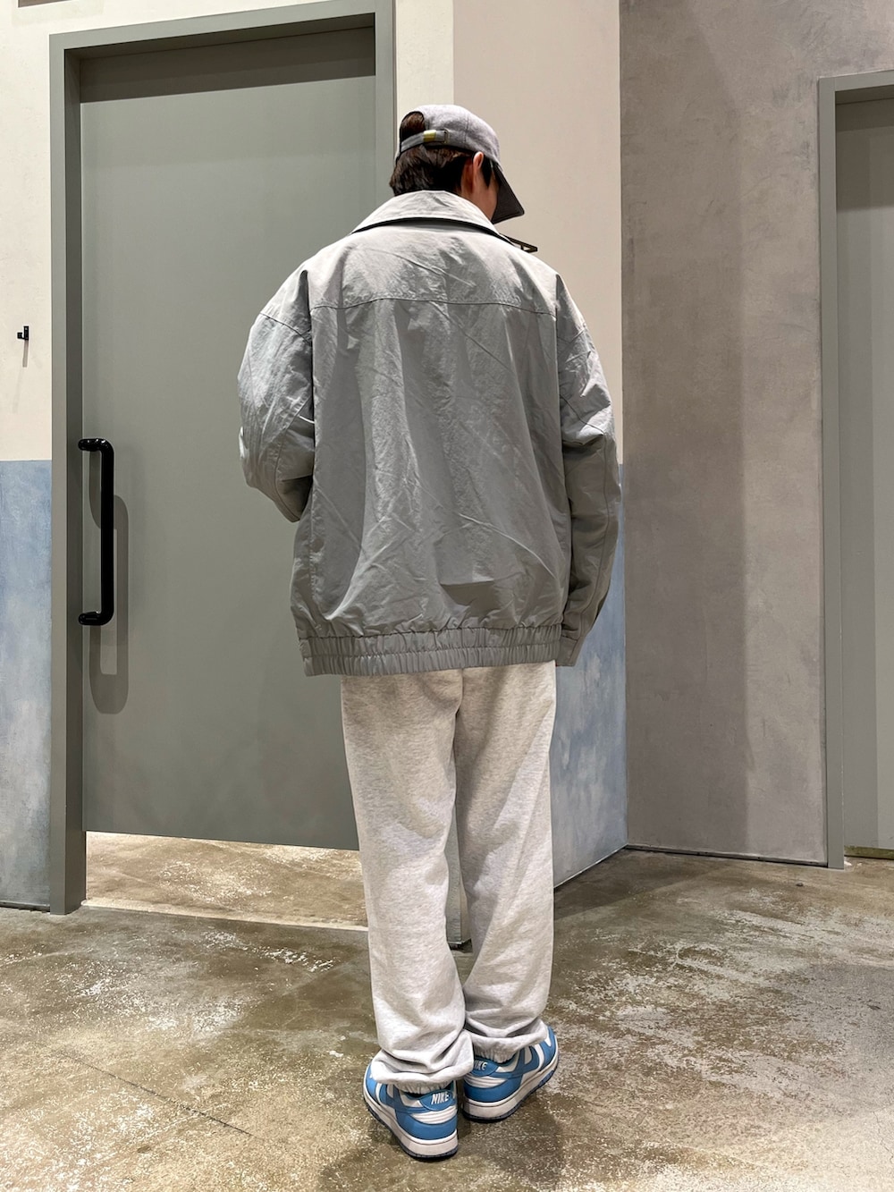 ブルー系のスニーカー、グレー系のスウェットパンツ、グレー系のナイロンジャケットを着用したメンズの冬コーディネートの2枚目の写真