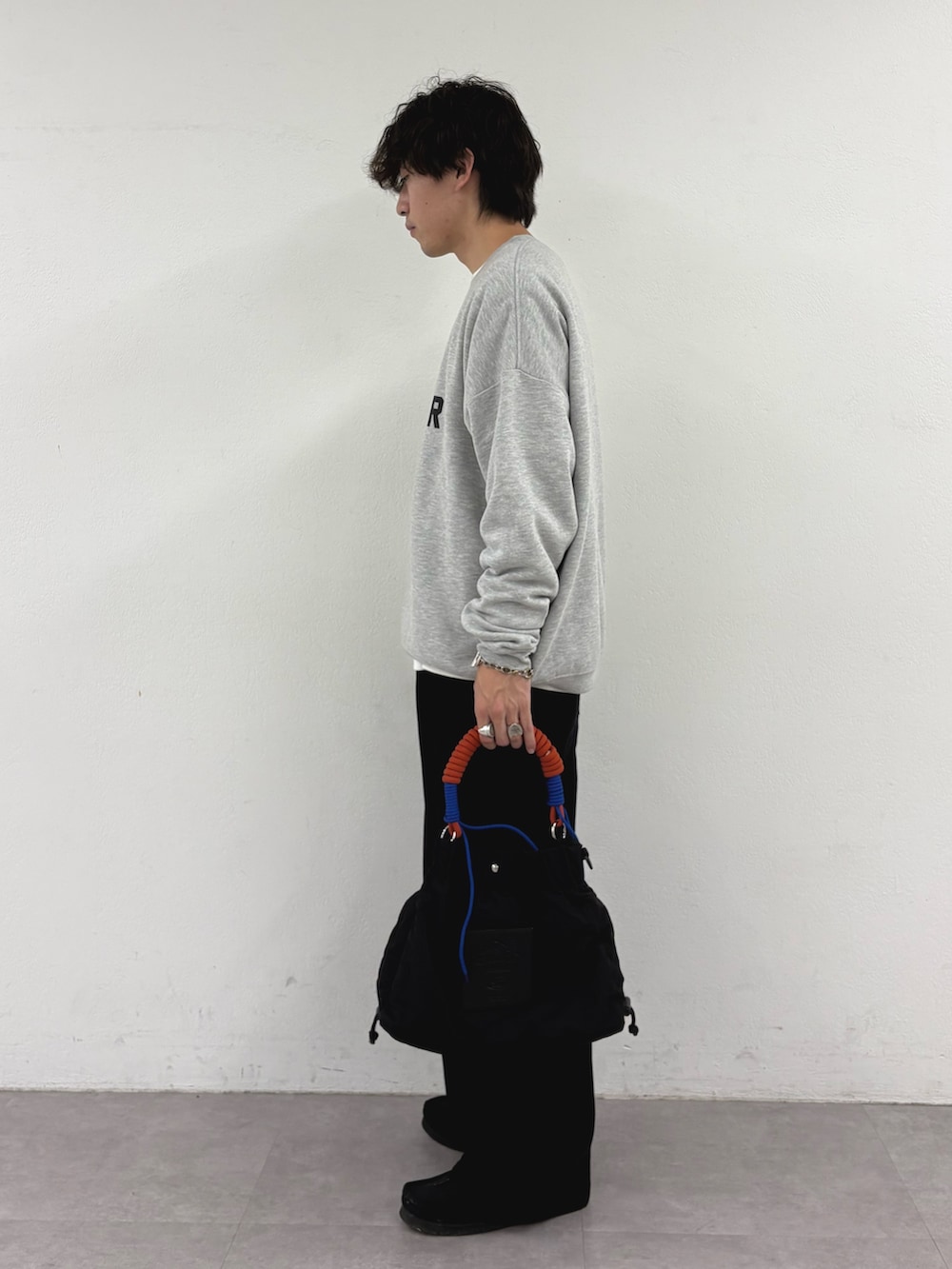 グレー系のスウェット、ブラック系のデニムパンツ、ブラック系のトートバッグを着用したメンズの秋コーディネートの2枚目の写真