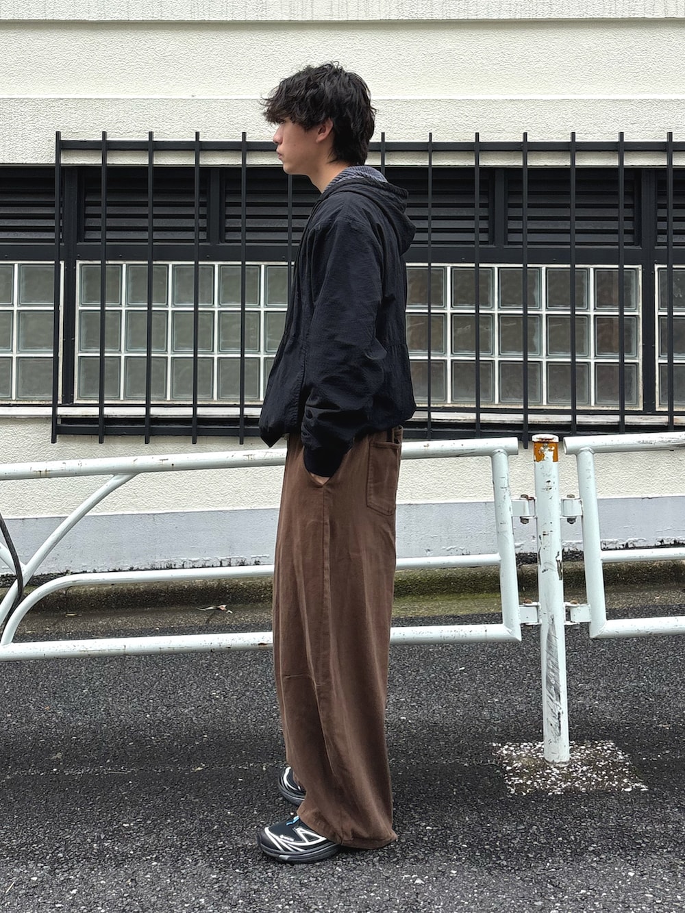 ブラック系のマウンテンパーカー、グレー系のTシャツ/カットソー、ブラウン系のデニムパンツを着用したメンズの秋コーディネートの2枚目の写真