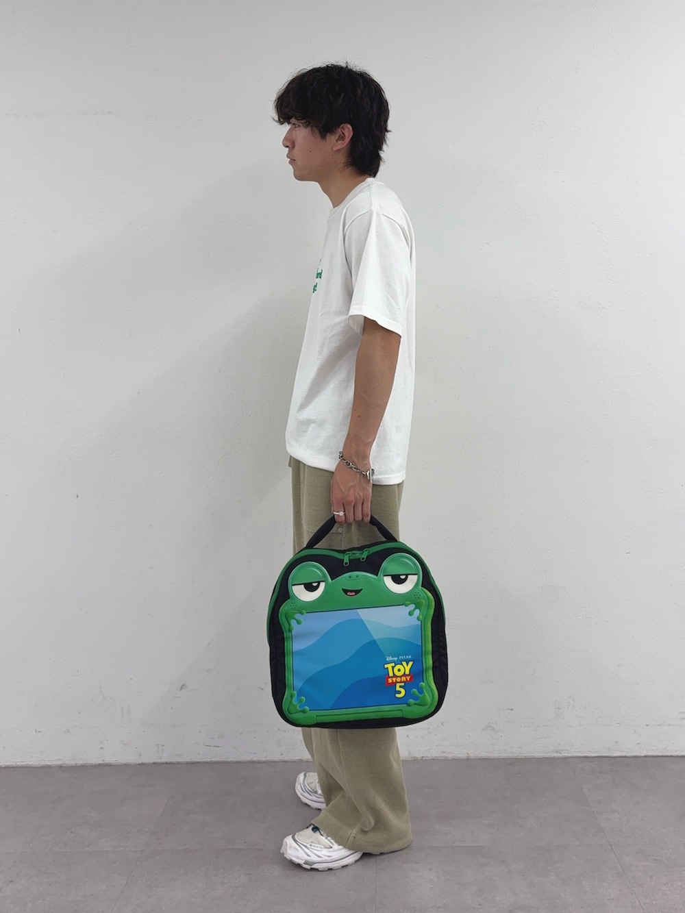 ホワイト系のTシャツ/カットソー、ベージュ系のスウェットパンツ、ブラック系のPC・タブレットケースを着用したメンズの春コーディネートの2枚目の写真
