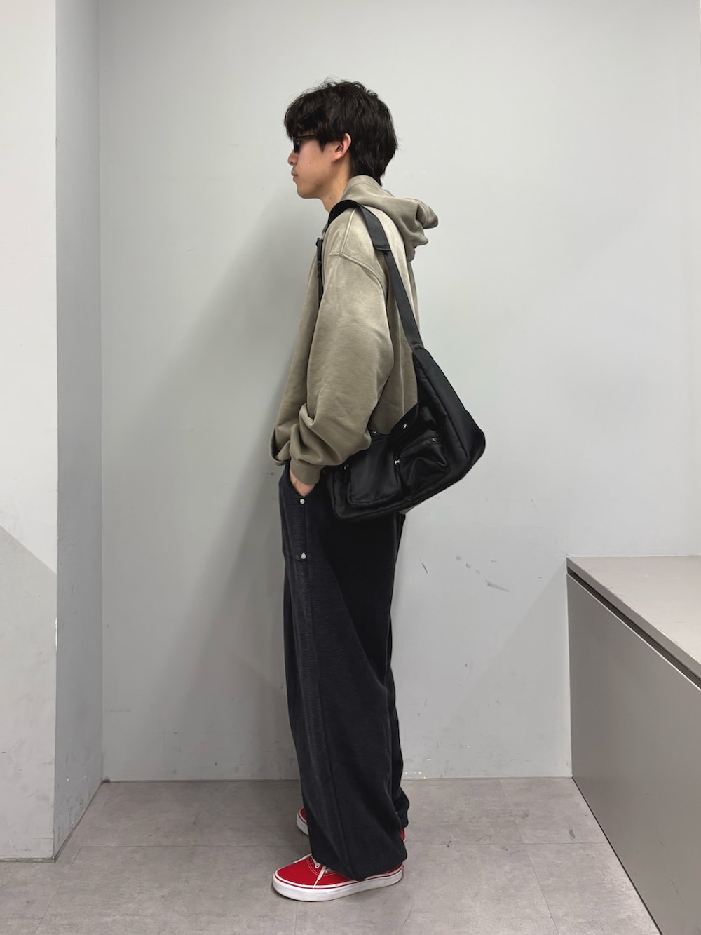 ベージュ系のパーカー、ブラック系のショルダーバッグ、ブルー系のスウェットパンツを着用したメンズの春コーディネートの2枚目の写真