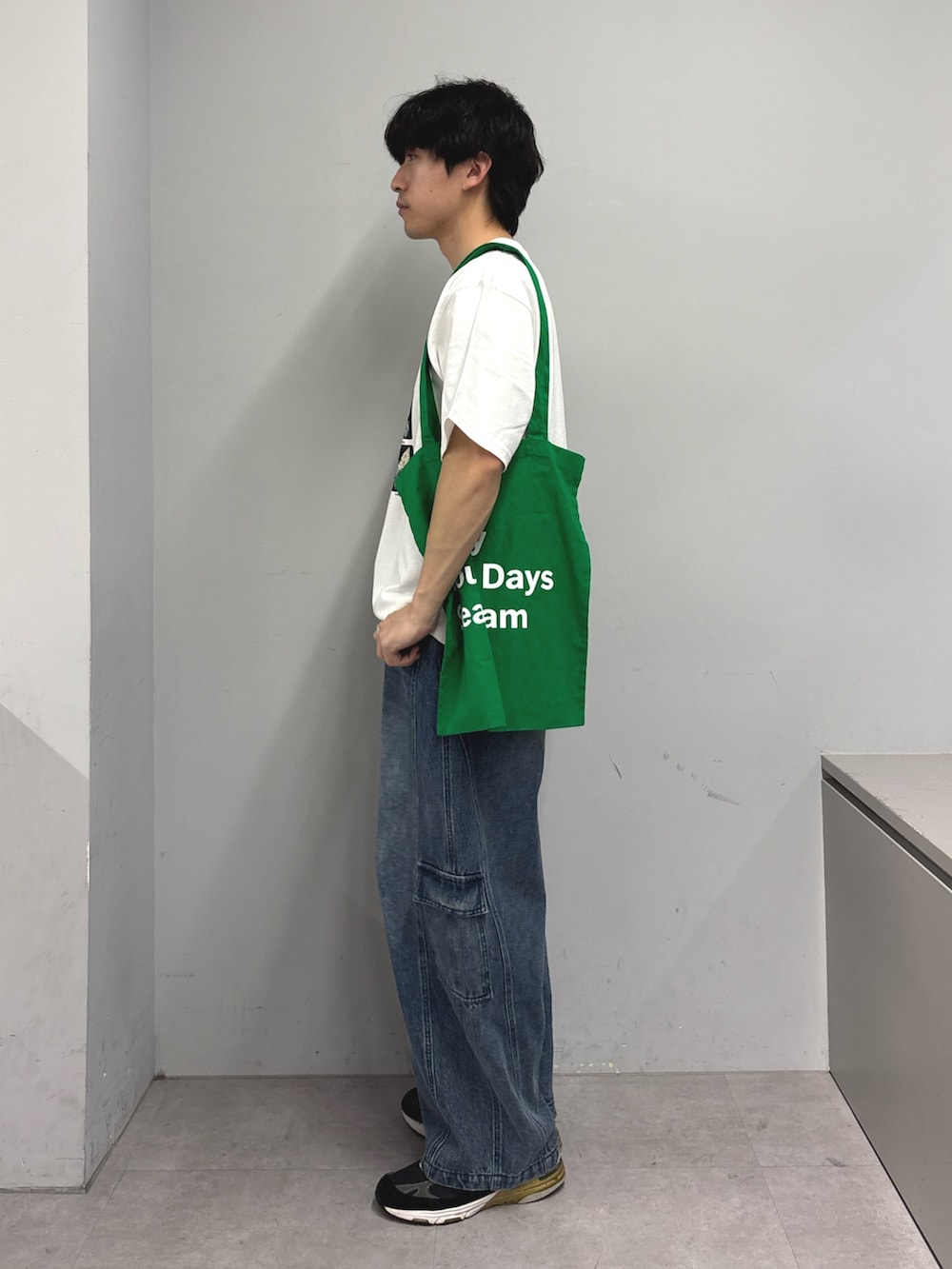 ホワイト系のTシャツ/カットソー、グリーン系のトートバッグ、ブルー系のカーゴパンツを着用したメンズの春コーディネートの2枚目の写真