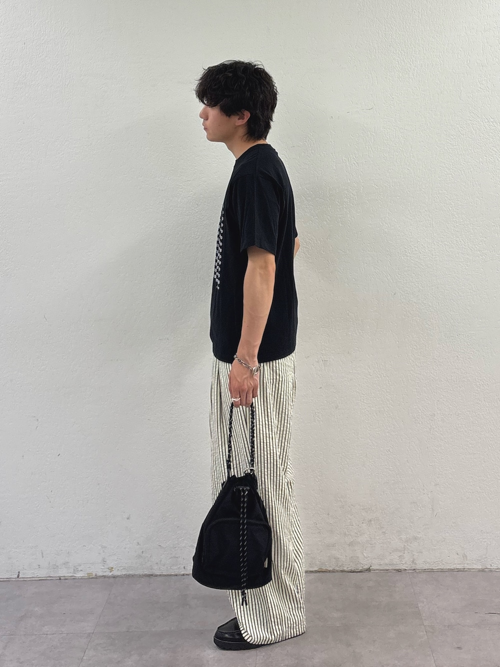 ブラック系のTシャツ/カットソー、ホワイト系のその他パンツ、ブラック系のトートバッグを着用したメンズの春コーディネートの2枚目の写真