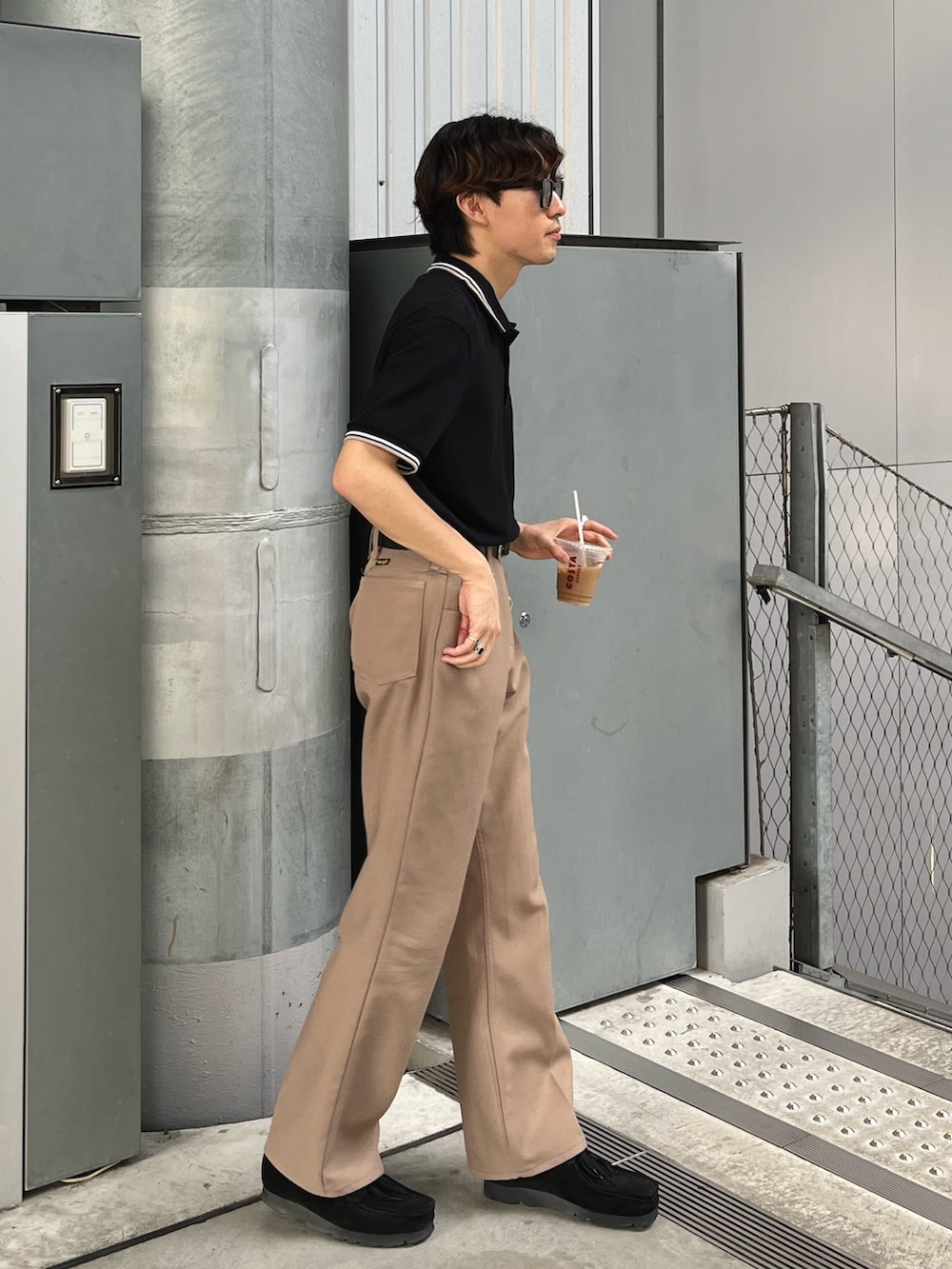 ブラック系のポロシャツ、ベージュ系のパンツ、ブラック系のスニーカーを着用したメンズの夏コーディネートの2枚目の写真