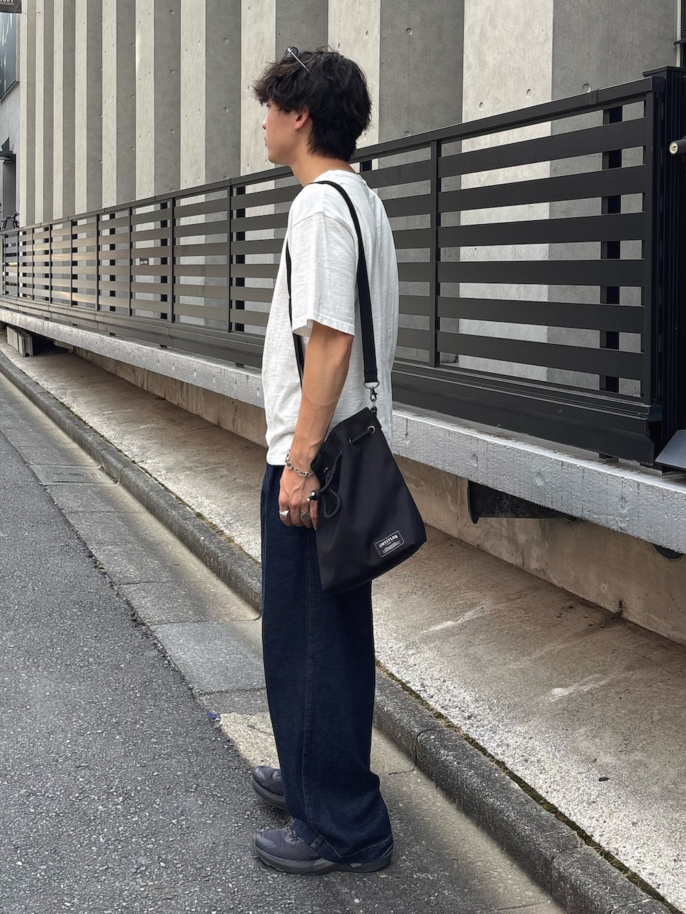 ホワイト系のTシャツ/カットソー、ブラック系のトートバッグ、ブルー系のデニムパンツを着用したメンズの夏コーディネートの2枚目の写真
