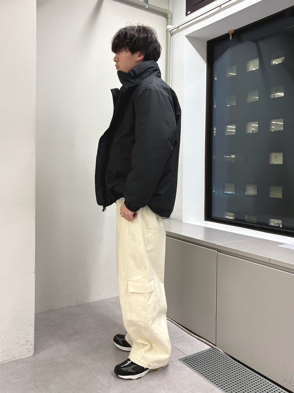 ブラック系のダウンジャケット/コート、オレンジ系のニット/セーター、ホワイト系のデニムパンツを着用したメンズの冬コーディネートの2枚目の写真