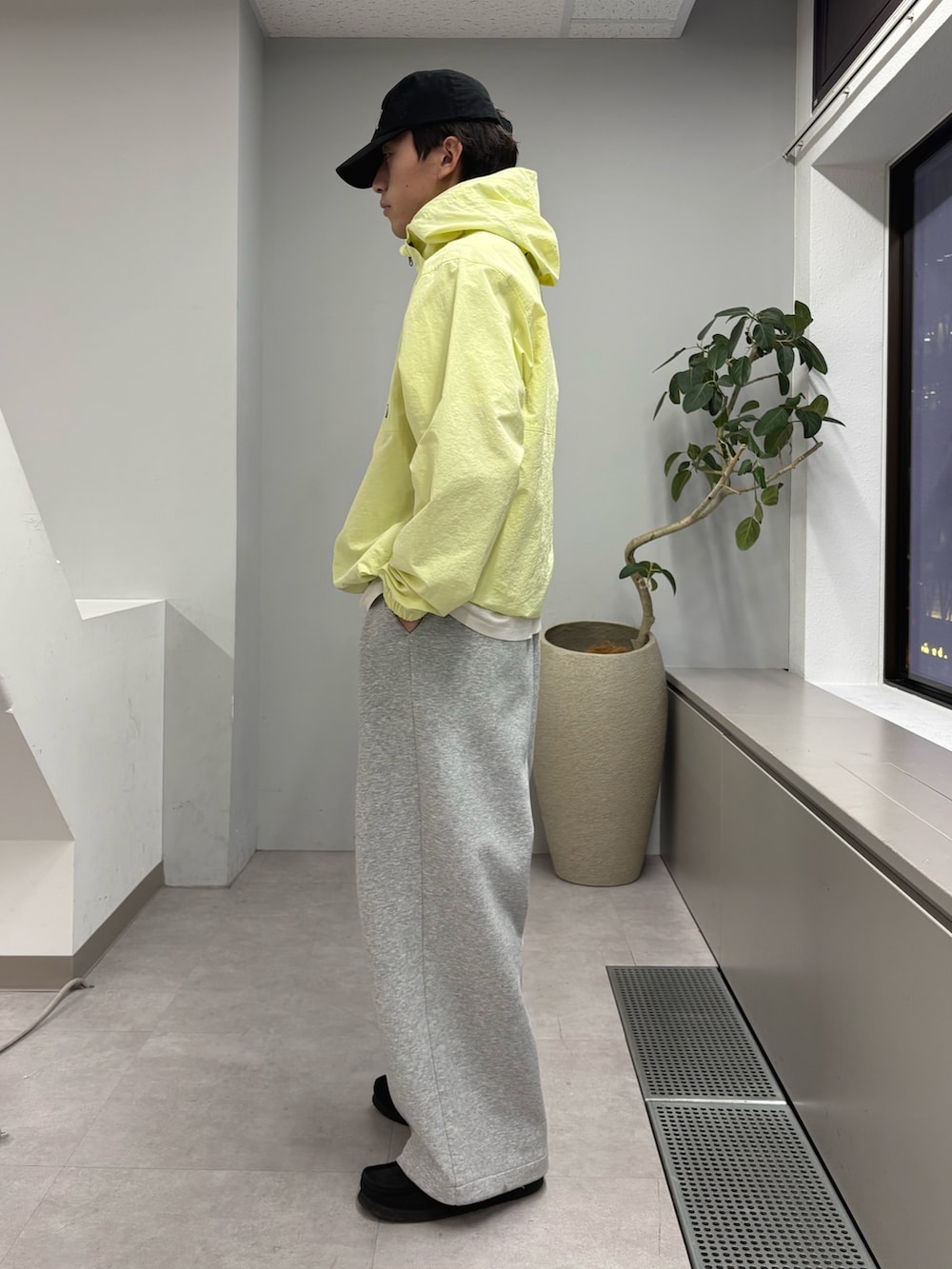 イエロー系のパーカー、グレー系のその他パンツ、ブラック系のキャップを着用したメンズの冬コーディネートの2枚目の写真