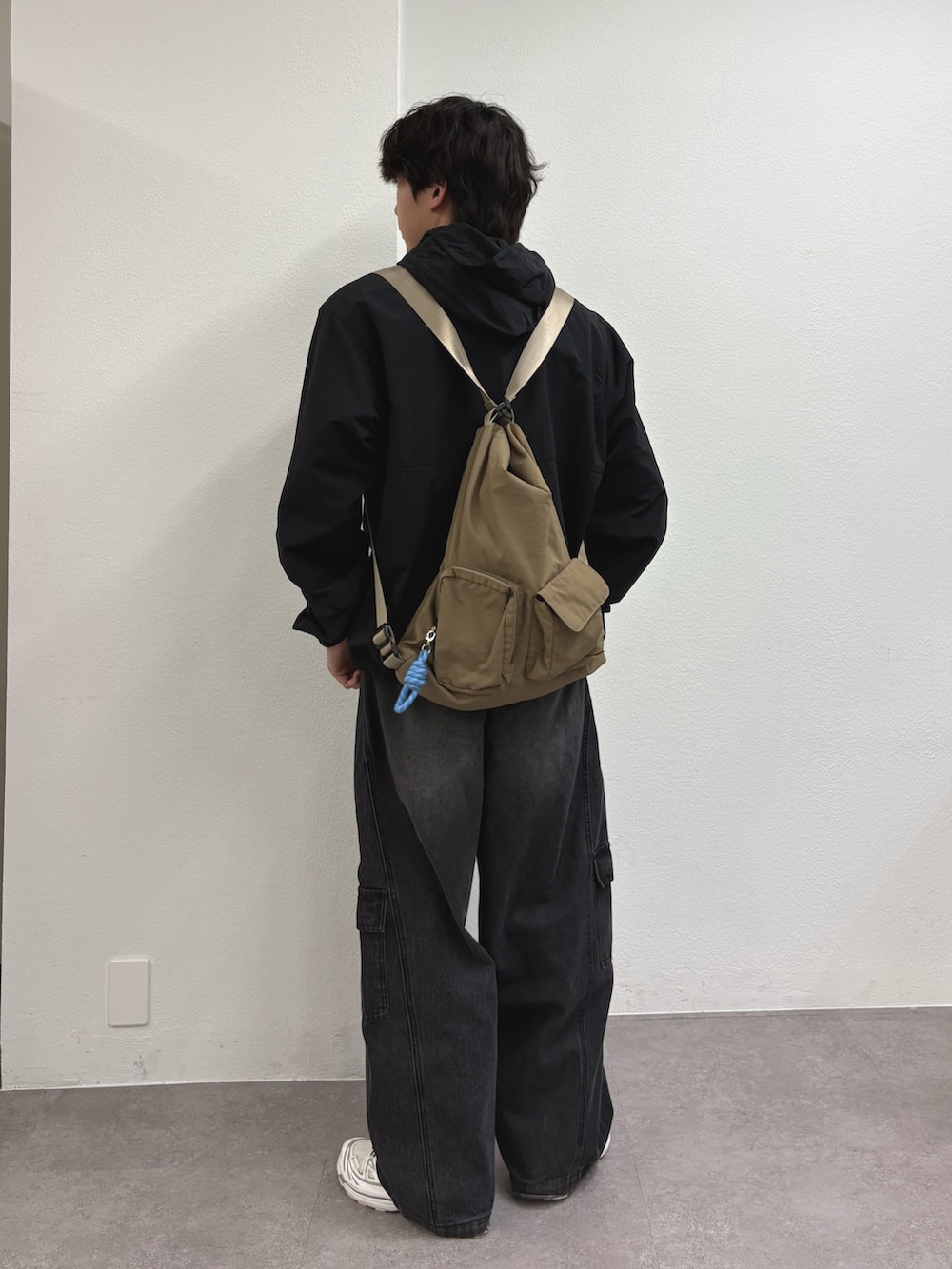 ブラック系のマウンテンパーカー、ブラック系のカーゴパンツ、ベージュ系のトートバッグを着用したメンズの春コーディネートの2枚目の写真