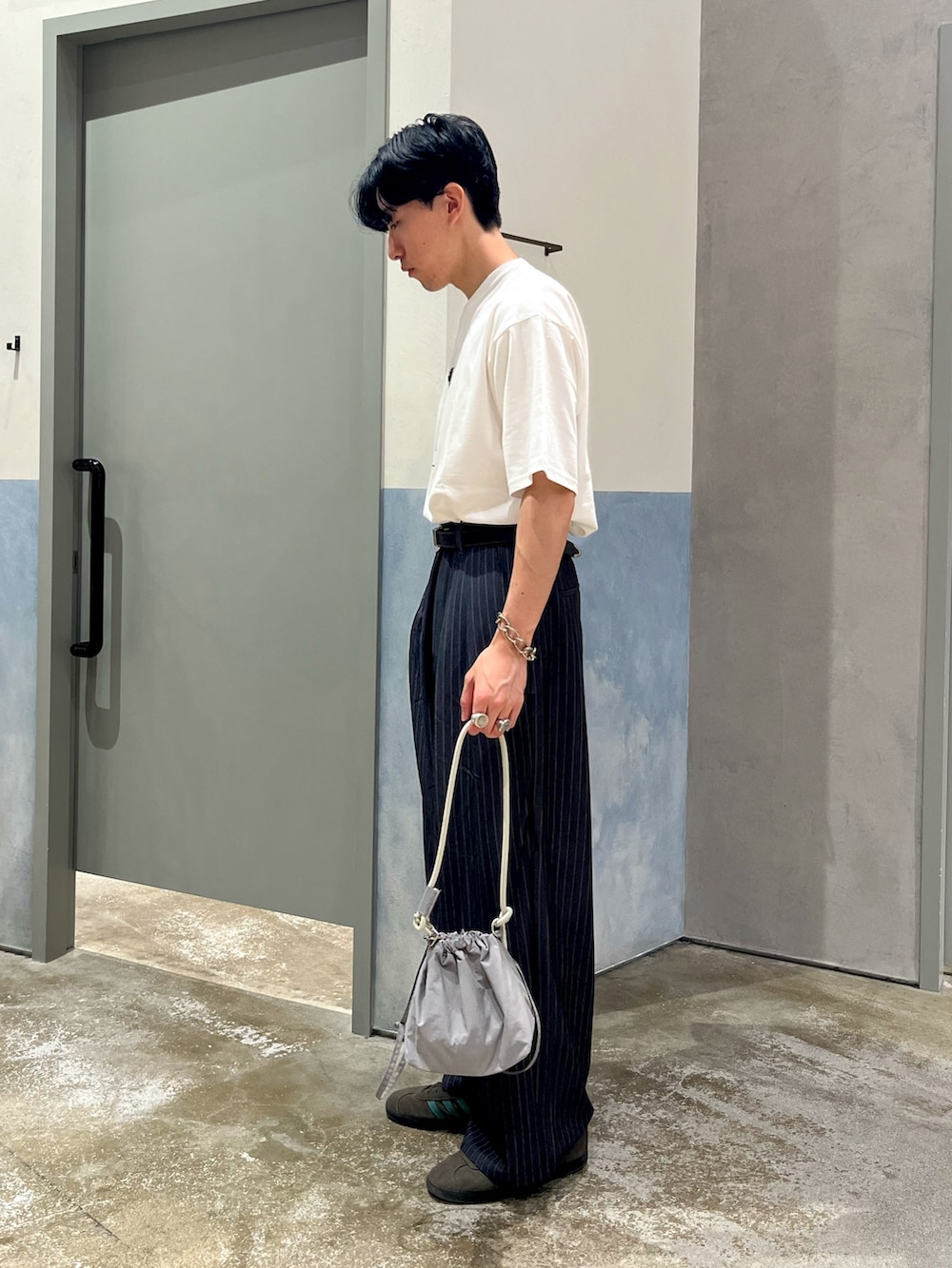 ホワイト系のTシャツ/カットソー、グレー系のスラックス、グレー系のショルダーバッグを着用したメンズの夏コーディネートの2枚目の写真