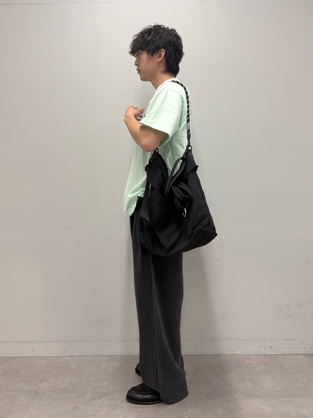グリーン系のTシャツ/カットソー、ブラック系のショルダーバッグ、ブラック系のスウェットパンツを着用したメンズの春コーディネートの2枚目の写真