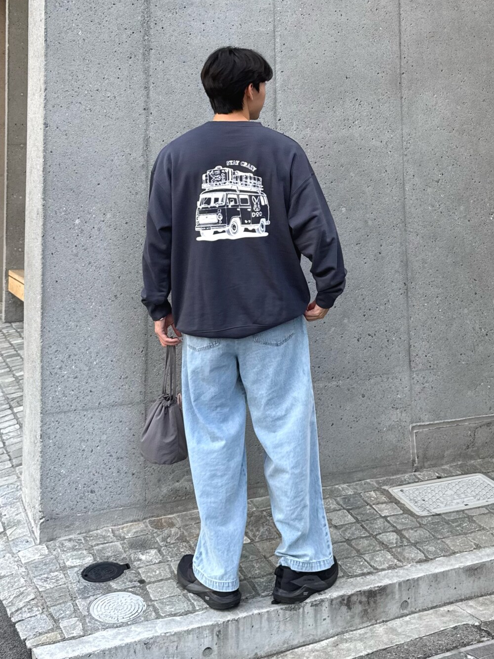 グレー系のスウェット、ブルー系のデニムパンツ、グレー系のトートバッグを着用したメンズの秋コーディネートの3枚目の写真