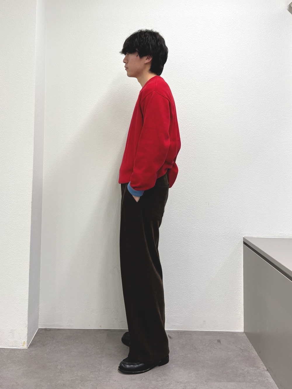 レッド系のニット/セーター、ブラウン系のその他パンツを着用したメンズの冬コーディネートの2枚目の写真