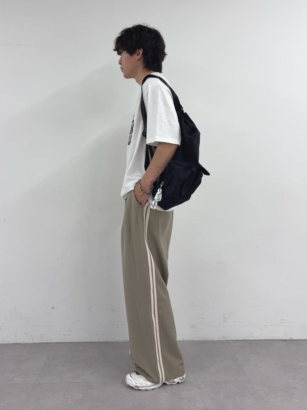 ホワイト系のTシャツ/カットソー、ブラック系のバックパック/リュック、ベージュ系のスラックスを着用したメンズの夏コーディネートの2枚目の写真
