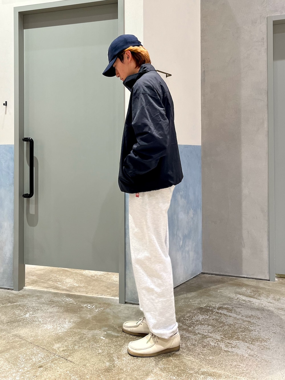 ホワイト系のスニーカー、グレー系のスウェットパンツ、ブラック系のナイロンジャケットを着用したメンズの秋コーディネートの2枚目の写真