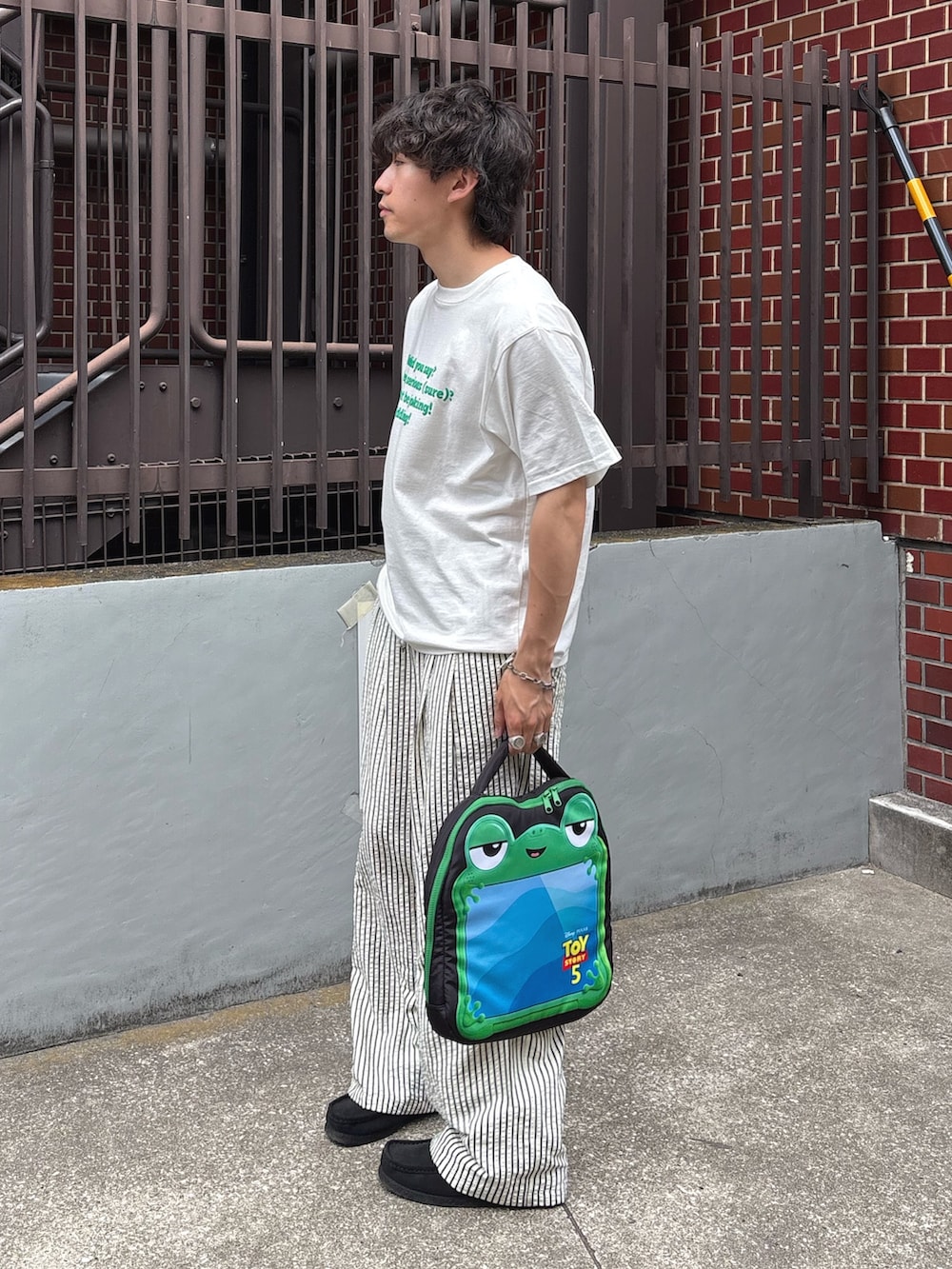 ホワイト系のTシャツ/カットソー、ホワイト系のその他パンツ、ブラック系のPC・タブレットケースを着用したメンズの春コーディネートの2枚目の写真