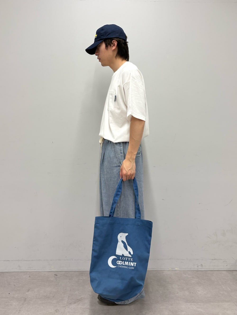 ホワイト系のTシャツ/カットソー、ブルー系のデニムパンツ、ブルー系のトートバッグを着用したメンズの夏コーディネートの2枚目の写真