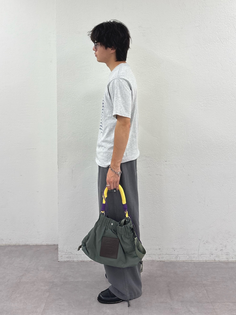 グレー系のTシャツ/カットソー、グレー系のスウェットパンツ、グリーン系のトートバッグを着用したメンズの夏コーディネートの2枚目の写真