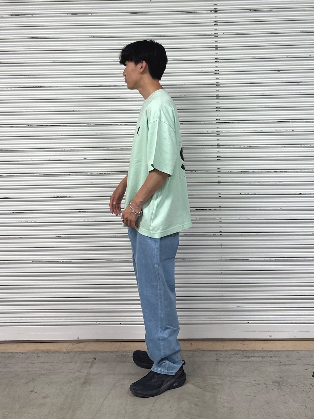 グリーン系のTシャツ/カットソー、ブルー系のデニムパンツを着用したメンズの春コーディネートの3枚目の写真