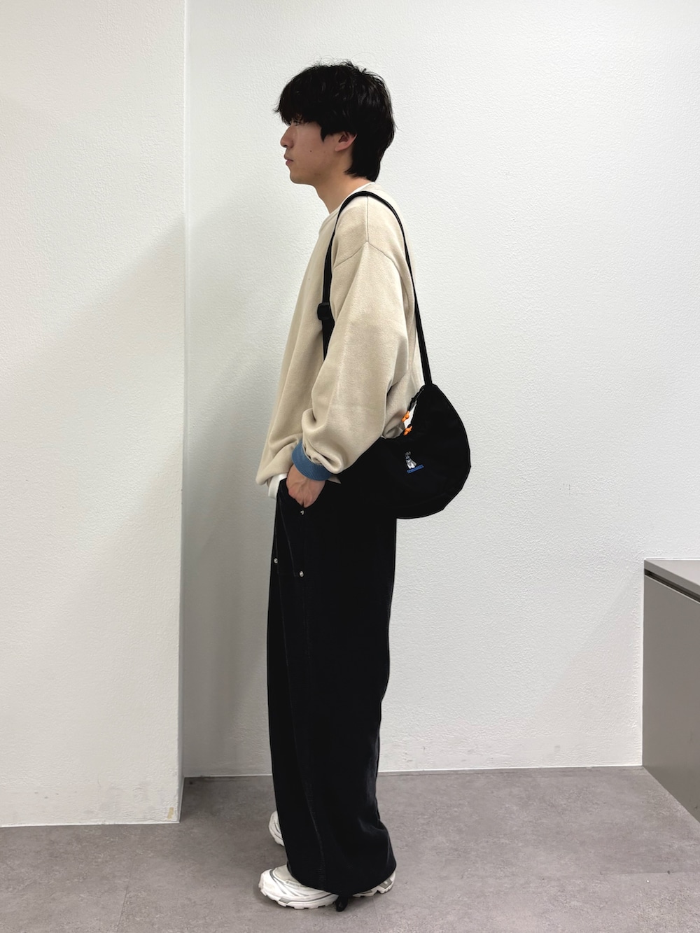 ホワイト系のニット/セーター、ブラック系のショルダーバッグ、ブラック系のスウェットパンツを着用したメンズの春コーディネートの2枚目の写真