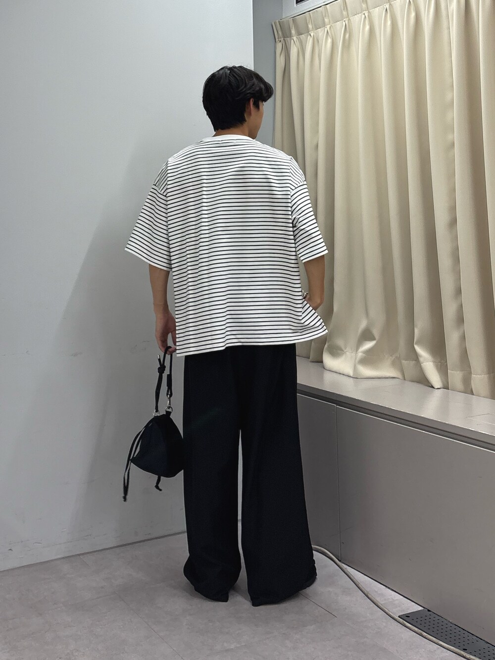 ホワイト系のTシャツ/カットソー、ブラック系のスラックス、ブラック系のショルダーバッグを着用したメンズの秋コーディネートの3枚目の写真