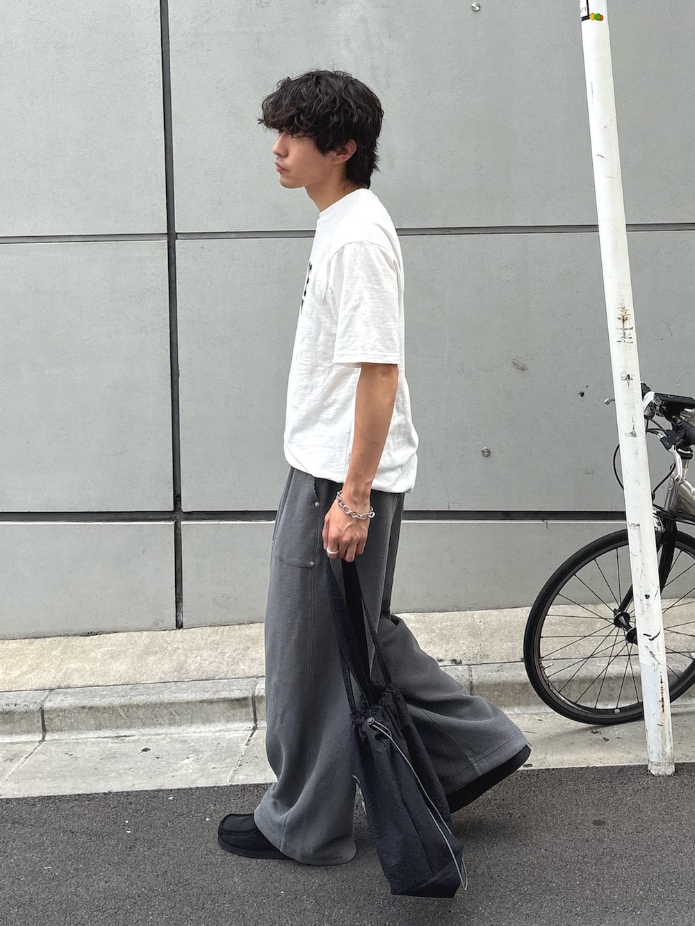 ホワイト系のTシャツ/カットソー、グレー系のスウェットパンツ、ブラック系のトートバッグを着用したメンズの夏コーディネートの2枚目の写真