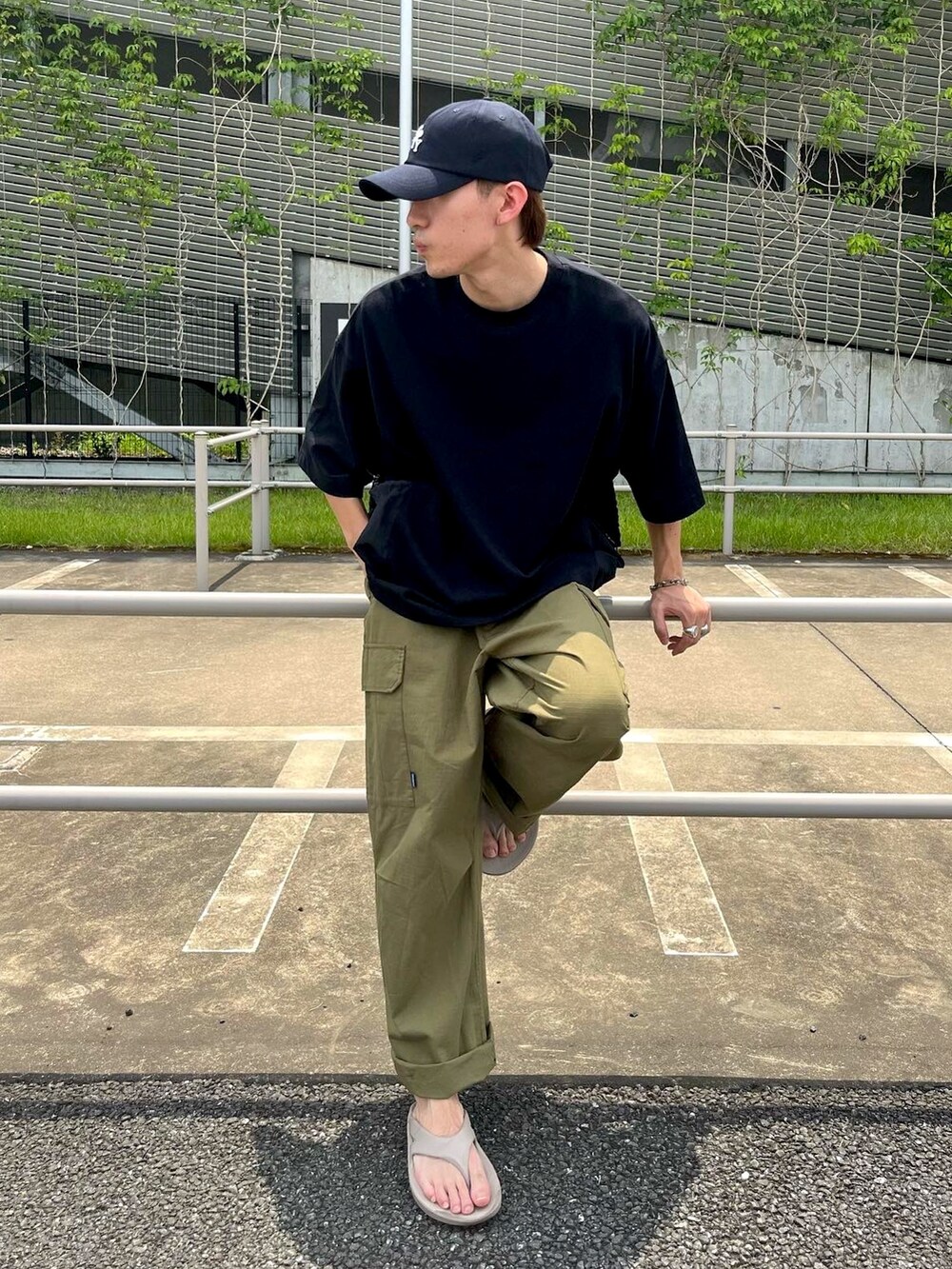 ベージュ系のサンダル、グリーン系のカーゴパンツ、ブラック系のTシャツ/カットソーを着用したメンズの夏コーディネートの2枚目の写真