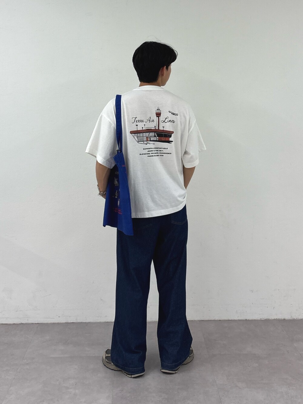ホワイト系のTシャツ/カットソー、ブルー系のトートバッグ、ブルー系のデニムパンツを着用したメンズの夏コーディネートの3枚目の写真
