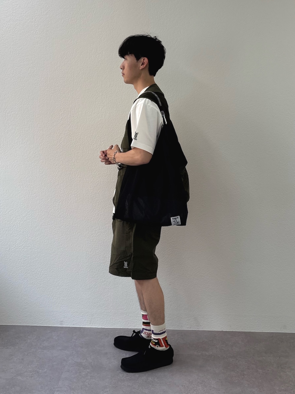 ホワイト系のTシャツ/カットソー、グリーン系のベスト、ブラック系のトートバッグを着用したメンズの春コーディネートの2枚目の写真