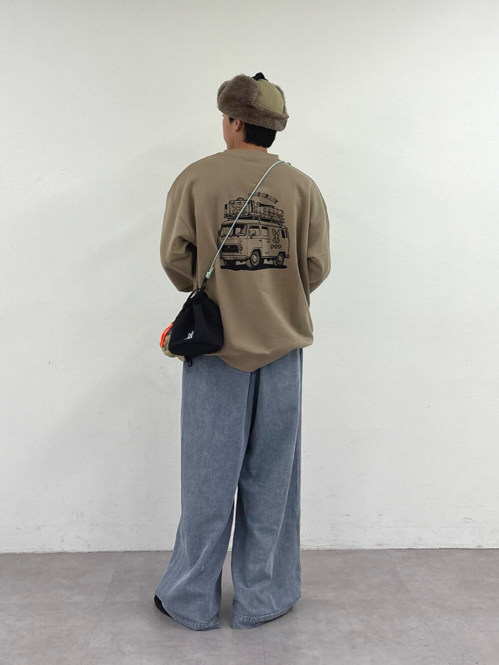 ベージュ系のスウェット、ブラック系のトートバッグ、ブルー系のデニムパンツを着用したメンズの秋コーディネートの3枚目の写真