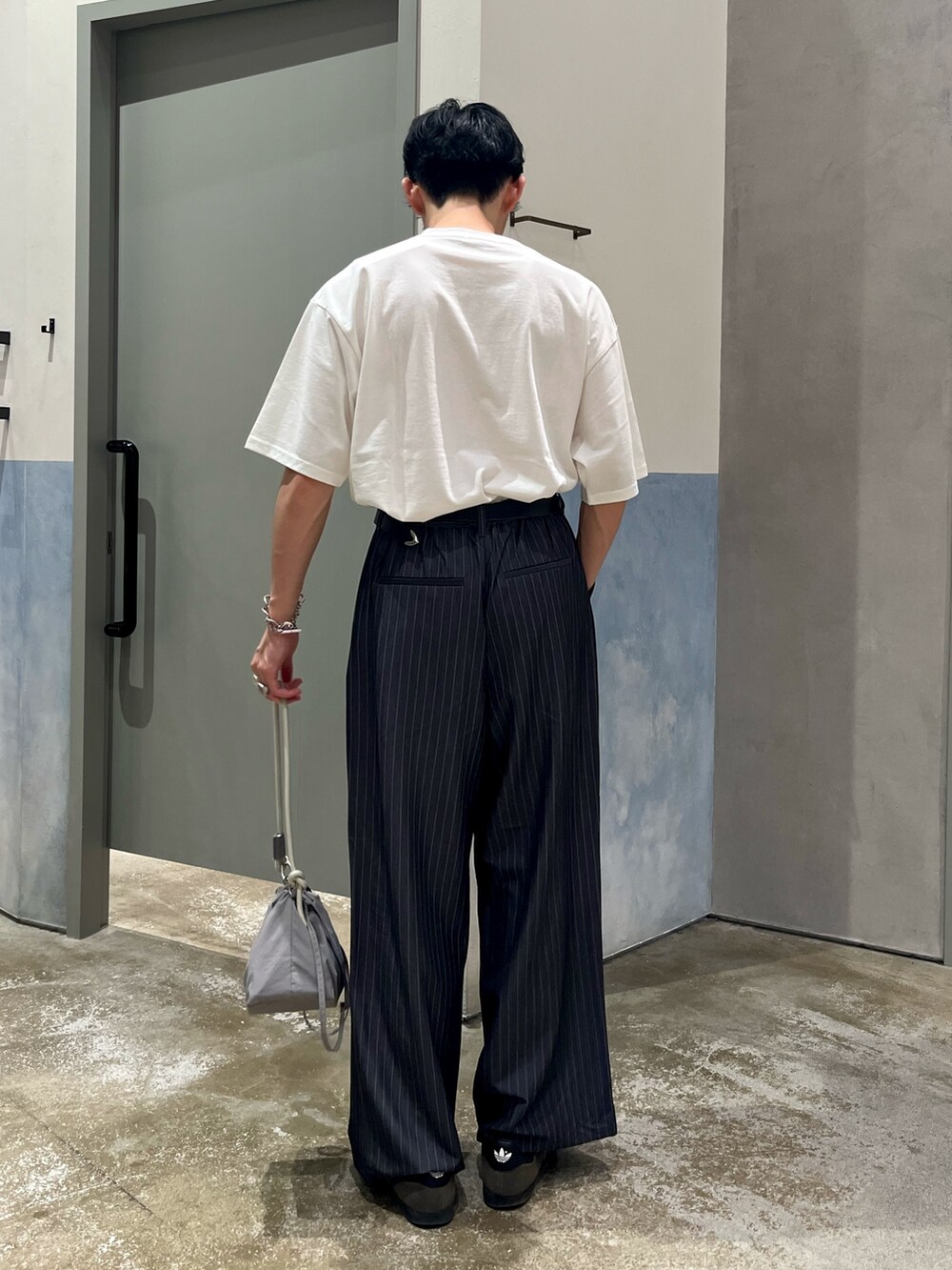 ホワイト系のTシャツ/カットソー、グレー系のスラックス、グレー系のショルダーバッグを着用したメンズの夏コーディネートの3枚目の写真