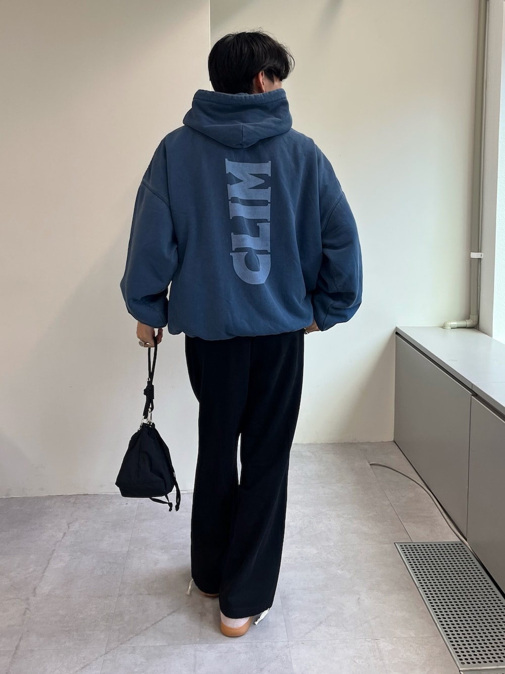 ピンク系のスニーカー、ブラック系のショルダーバッグ、ブラック系のチノパンツを着用したメンズの秋コーディネートの2枚目の写真