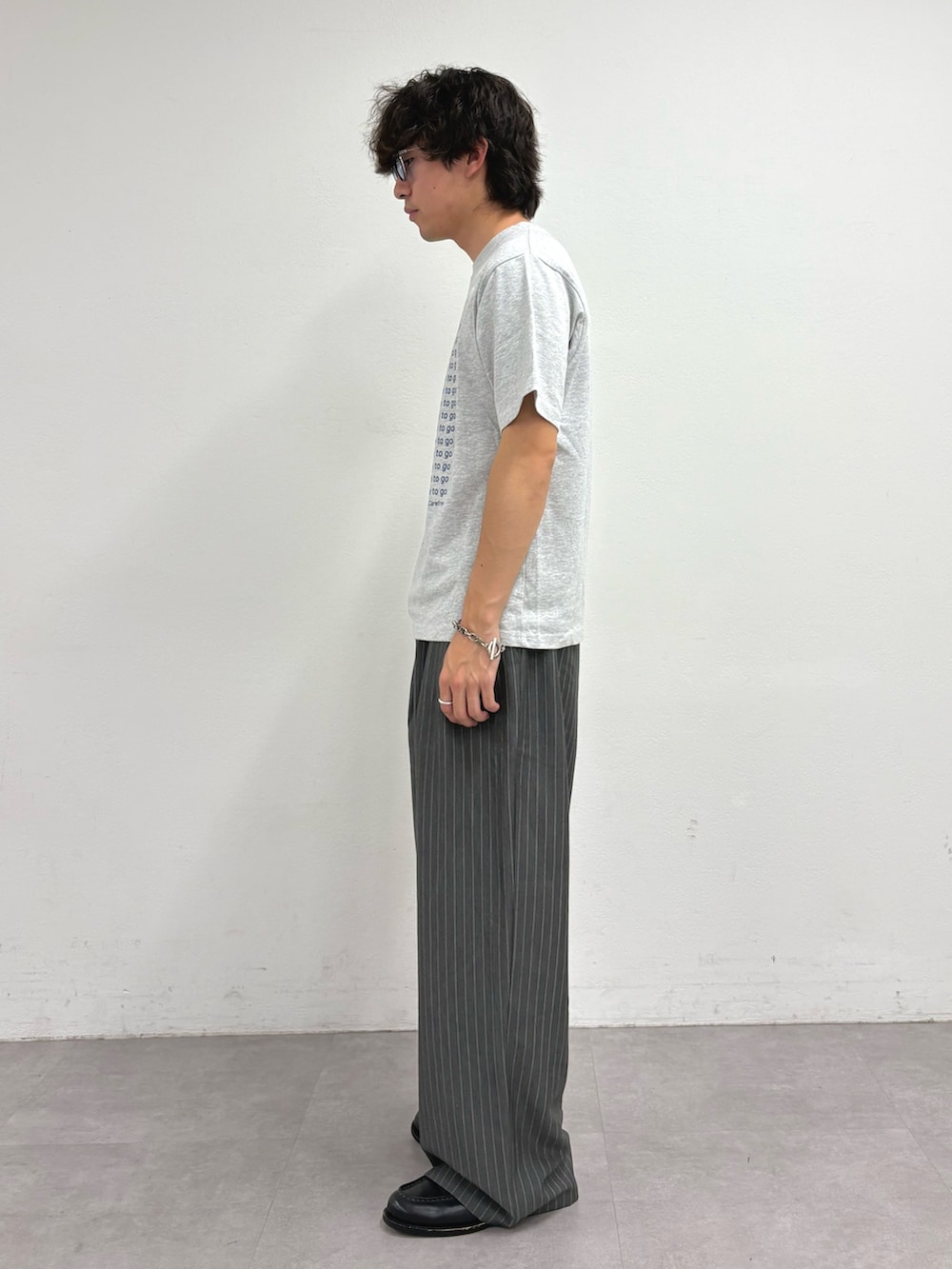 グレー系のTシャツ/カットソー、グレー系のスラックスを着用したメンズの夏コーディネートの2枚目の写真