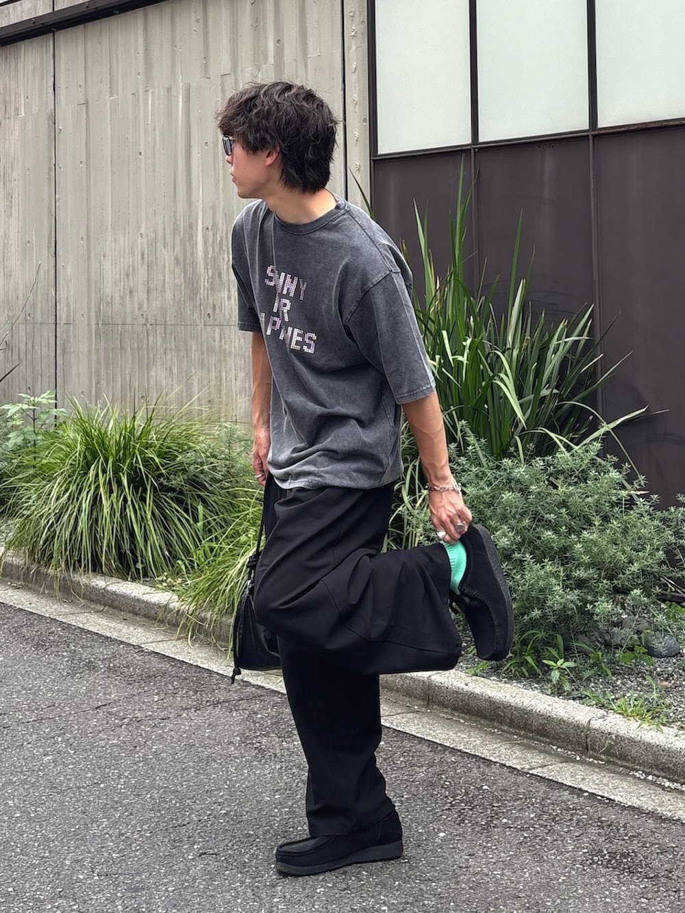 ブラック系のTシャツ/カットソー、ブラック系のスラックス、ブラック系のショルダーバッグを着用したメンズの夏コーディネートの2枚目の写真