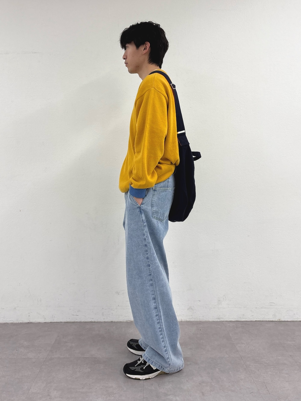 イエロー系のニット/セーター、ブルー系のショルダーバッグ、ブルー系のデニムパンツを着用したメンズの春コーディネートの2枚目の写真