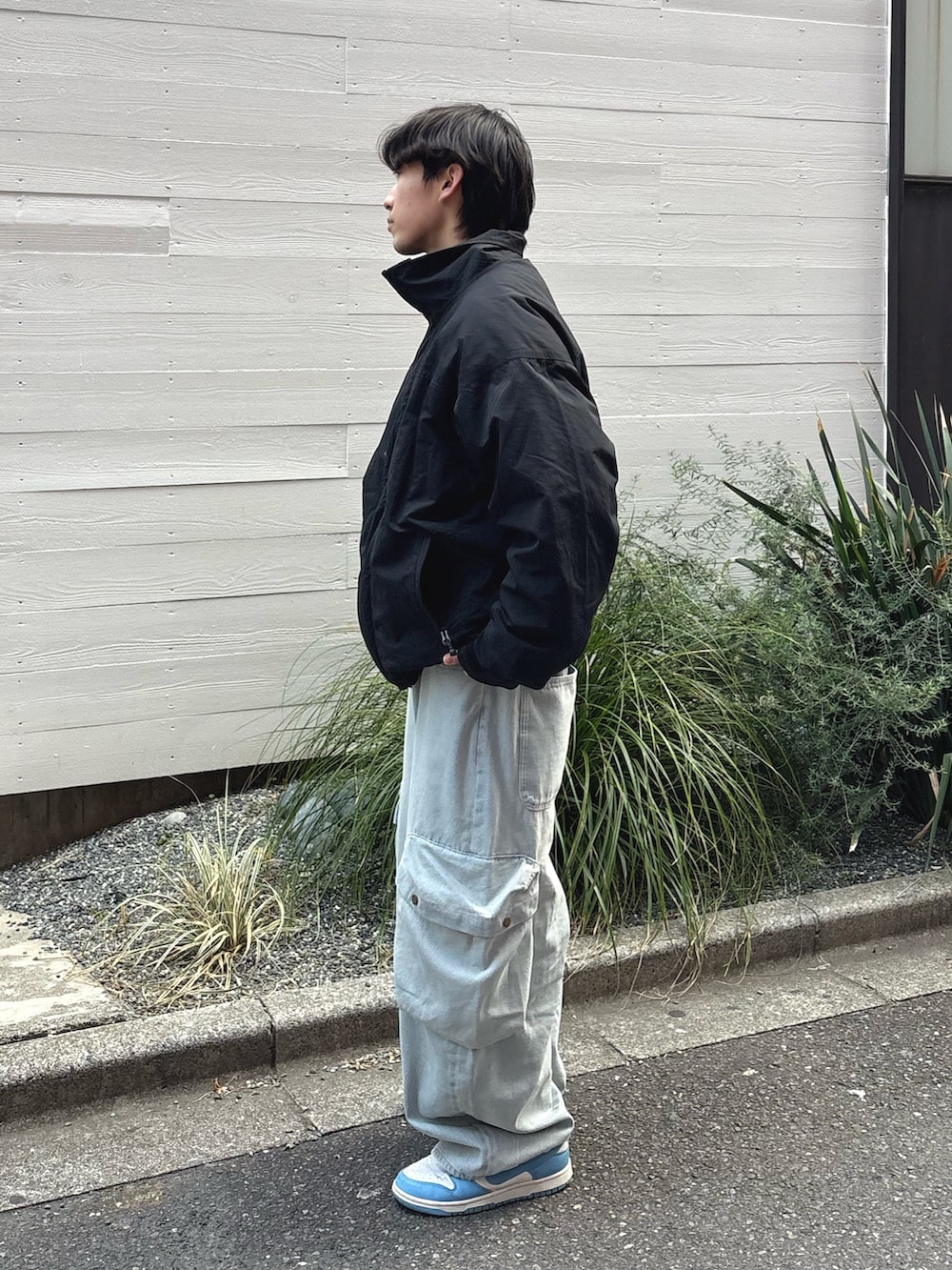 ブラック系のナイロンジャケット、ブルー系のデニムパンツを着用したメンズの冬コーディネートの2枚目の写真