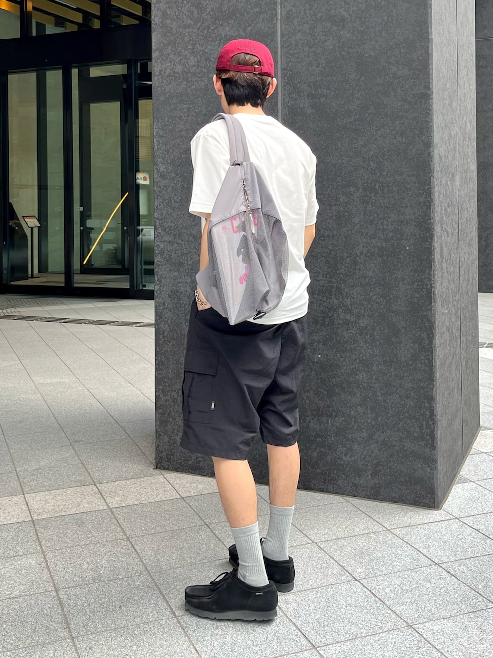 ブラック系のスニーカー、ブラック系のカーゴパンツ、ホワイト系のTシャツ/カットソーを着用したメンズの夏コーディネートの3枚目の写真