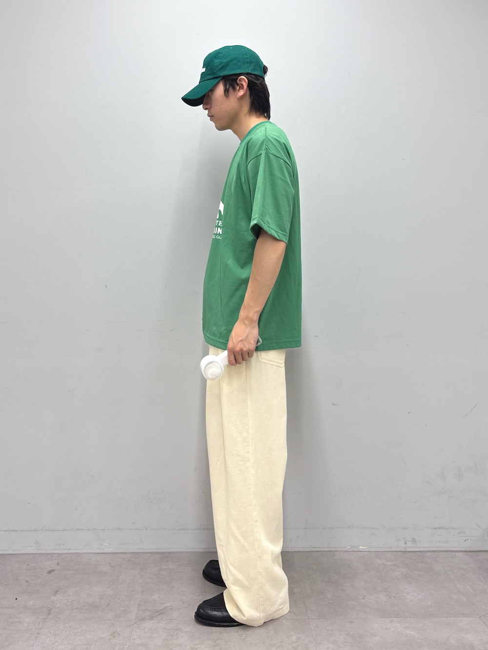 グリーン系のTシャツ/カットソー、ホワイト系のスラックス、グリーン系のキャップを着用したメンズの春コーディネートの2枚目の写真