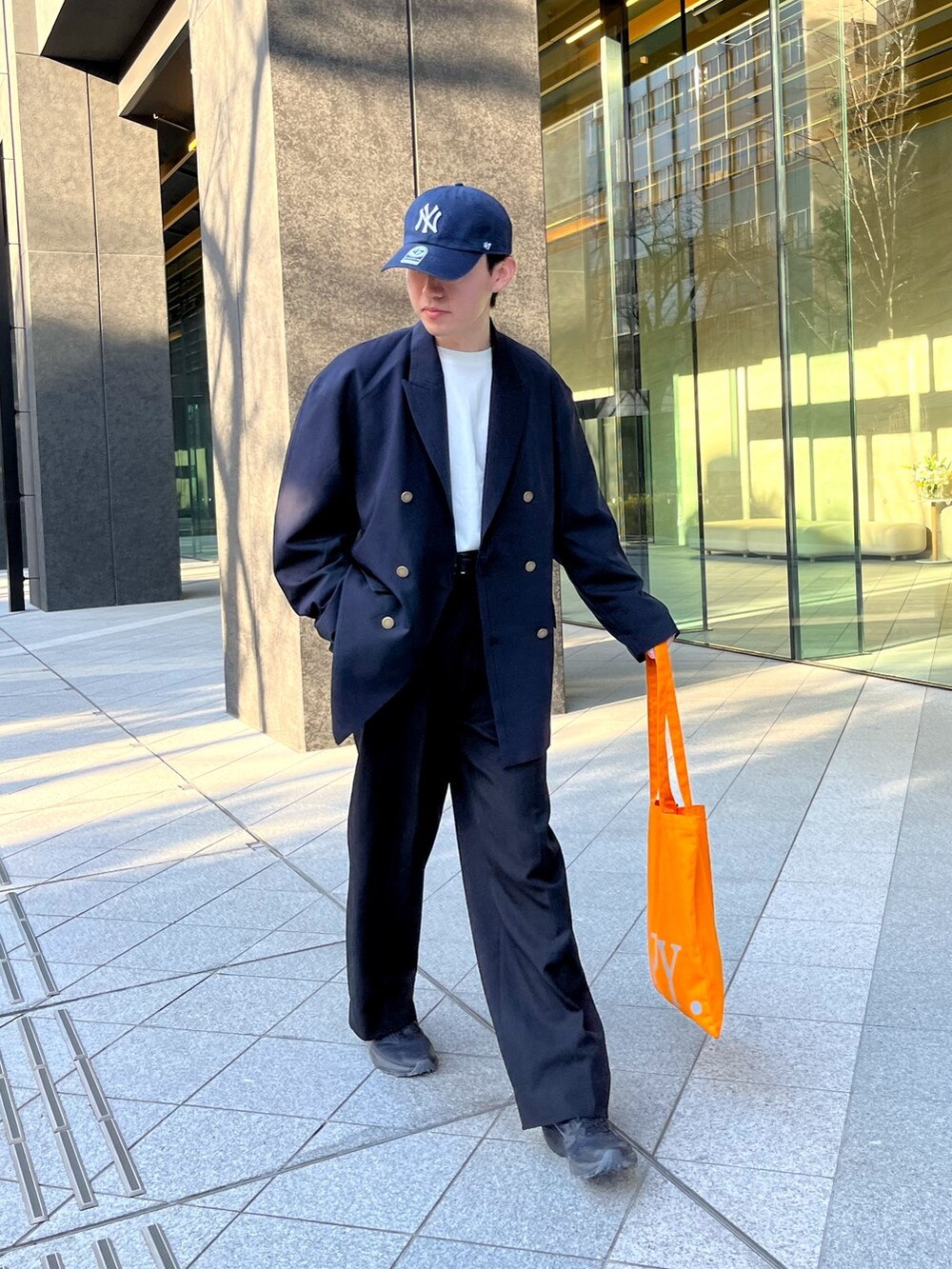 ブラック系のスニーカー、ブルー系のテーラードジャケット、ブラック系のスラックスを着用したメンズの春コーディネートの2枚目の写真