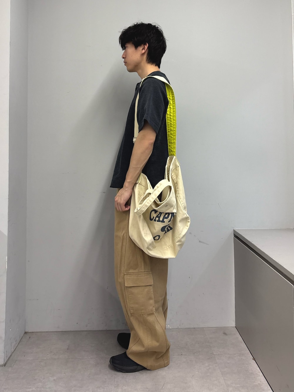 ブラック系のTシャツ/カットソー、ホワイト系のショルダーバッグ、ベージュ系のカーゴパンツを着用したメンズの春コーディネートの2枚目の写真