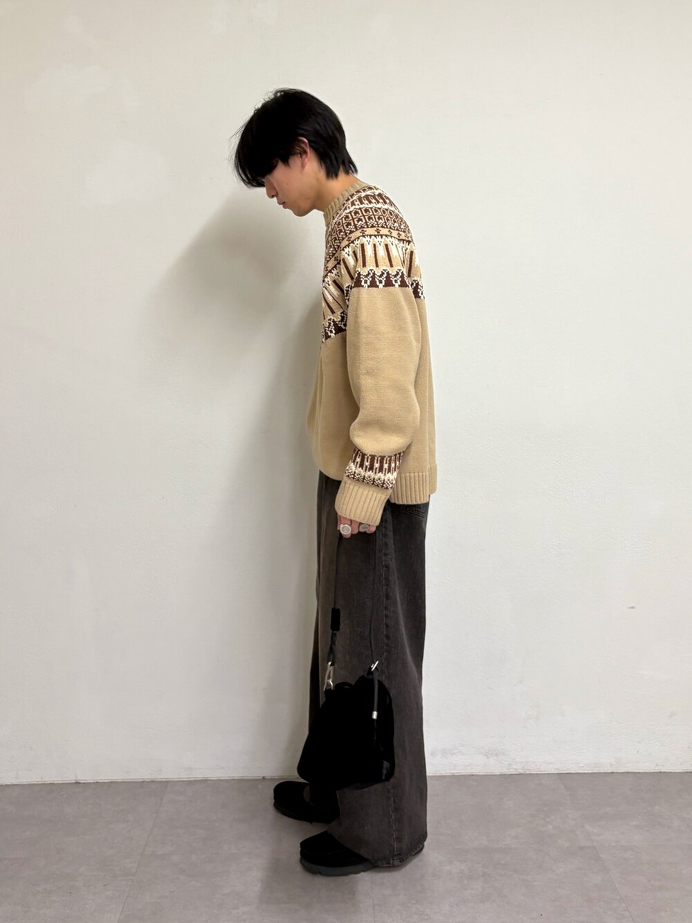 ブラウン系のニット/セーター、ブラック系のデニムパンツ、ブラック系のスニーカーを着用したメンズの冬コーディネートの2枚目の写真