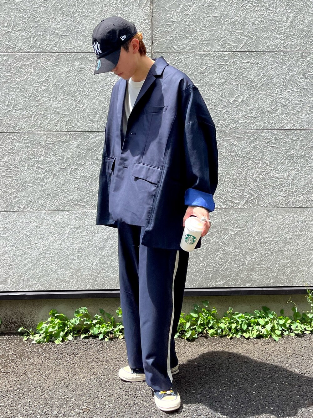 ブラック系のスニーカー、ベージュ系のスラックス、ブルー系のテーラードジャケットを着用したメンズの夏コーディネートの2枚目の写真