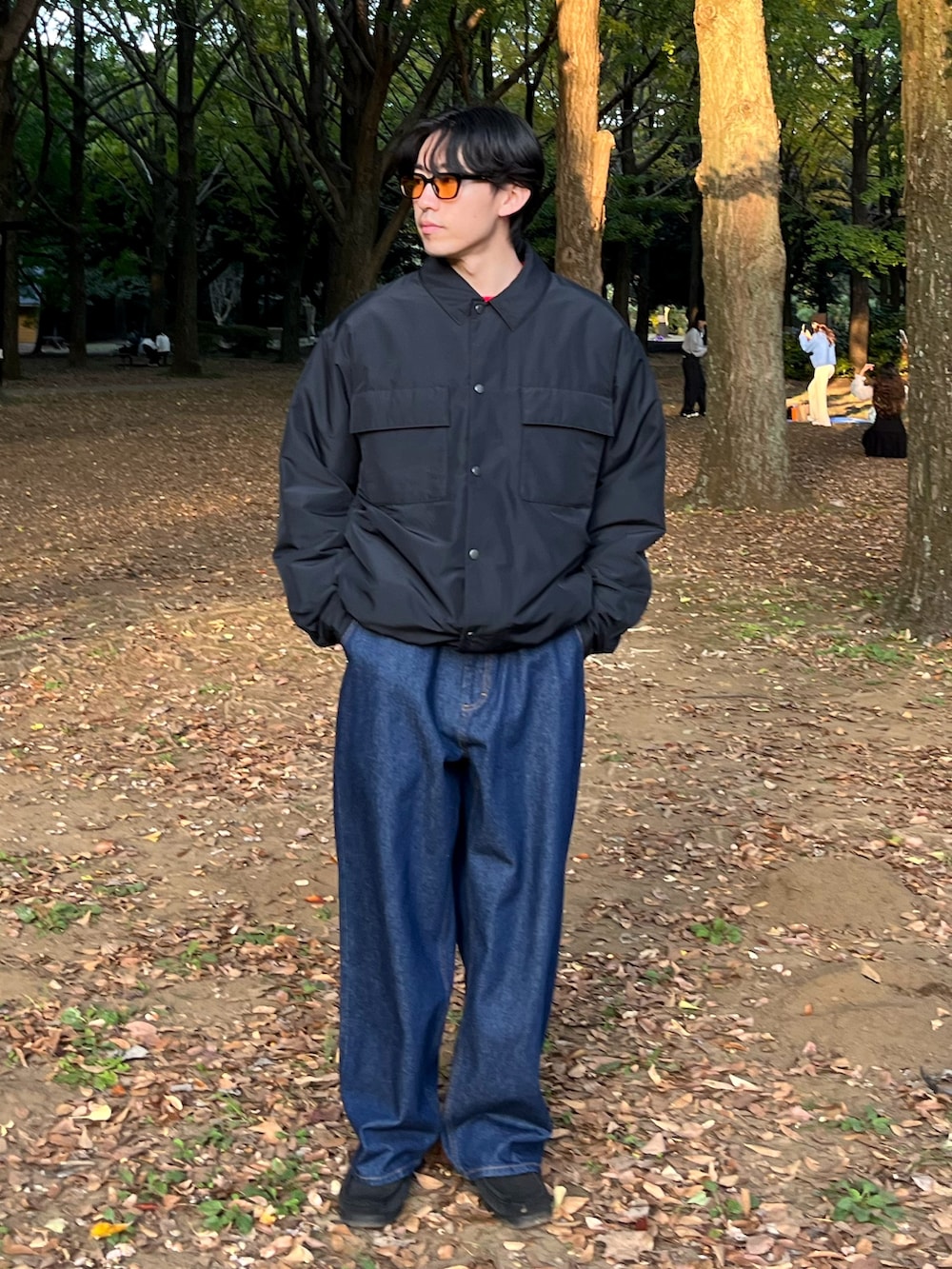 ブラック系のブルゾン、レッド系のニット/セーター、ブルー系のデニムパンツを着用したメンズの秋コーディネートの2枚目の写真