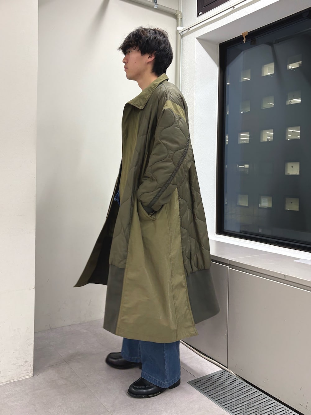 グリーン系のモッズコート、ホワイト系のニット/セーター、ブルー系のショルダーバッグを着用したメンズの冬コーディネートの2枚目の写真