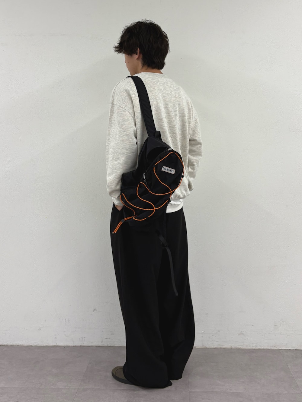 グレー系のスウェット、ブラック系のバックパック/リュック、ブラック系のスラックスを着用したメンズの秋コーディネートの2枚目の写真